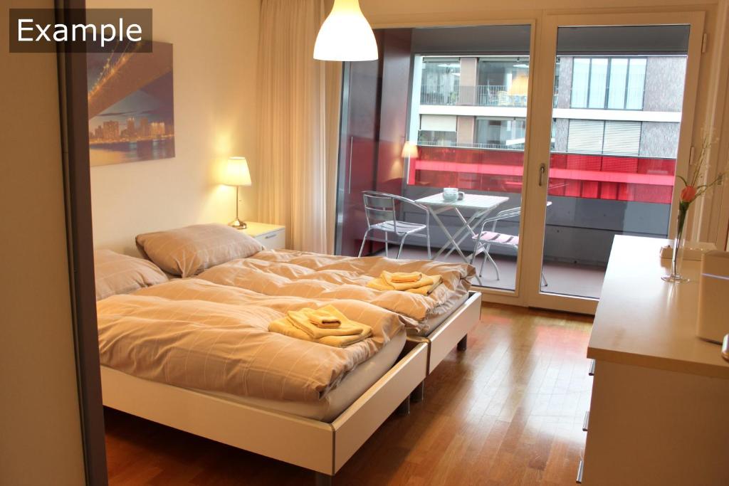 伯尔尼塞恩尼韦塔西城公寓的一间卧室配有一张床铺和一张桌子,并设有一个阳台