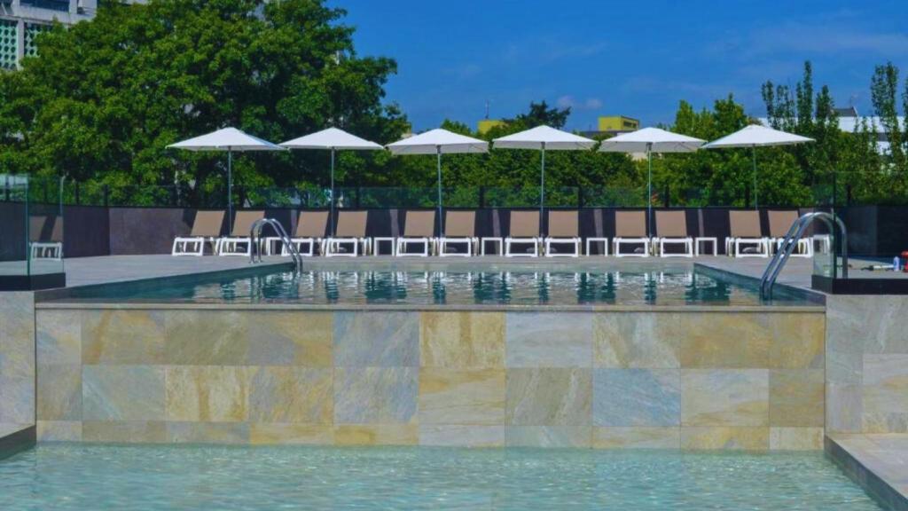 查韦斯Hotel Premium Chaves - Aquae Flaviae的一个带椅子和遮阳伞的游泳池