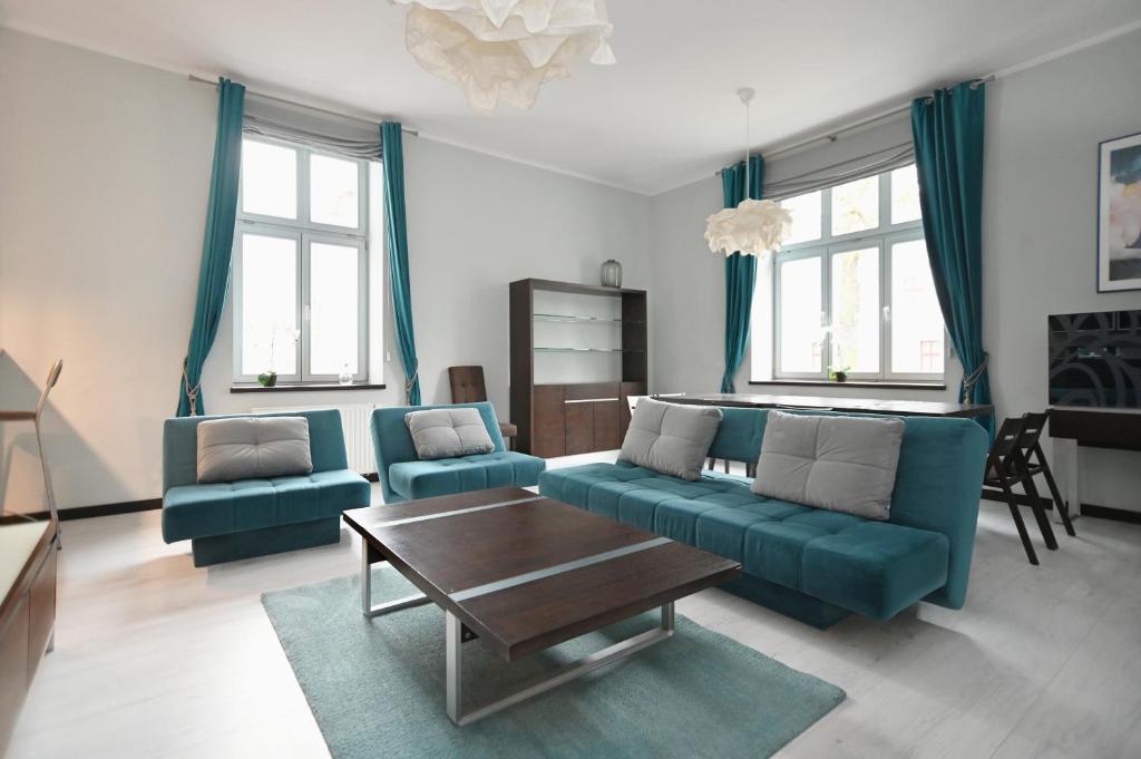 索波特Victus Apartamenty, Apartament Niebieski的客厅配有蓝色的沙发和咖啡桌
