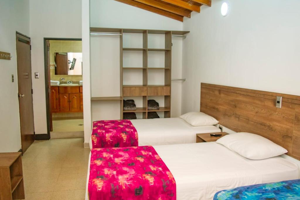 麦德林Hotel Boutique Estadio的一间卧室设有两张床和红色座椅。