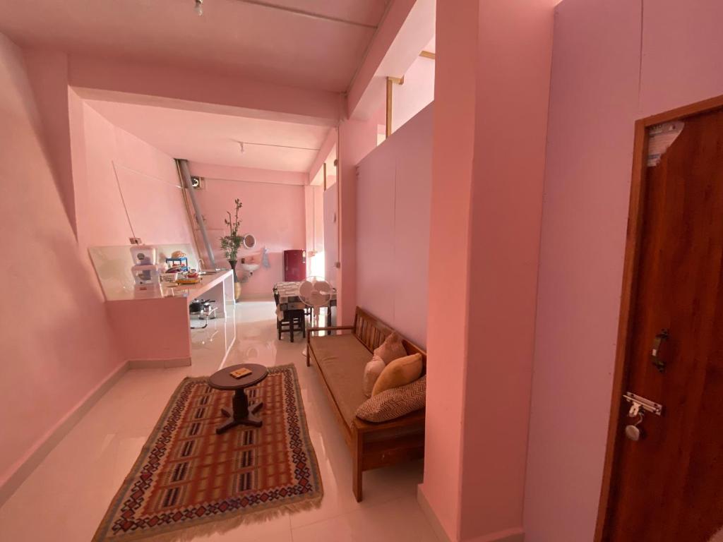 艾藻尔Aizawl Homestay的一间设有粉红色墙壁、一张沙发和一张桌子的房间