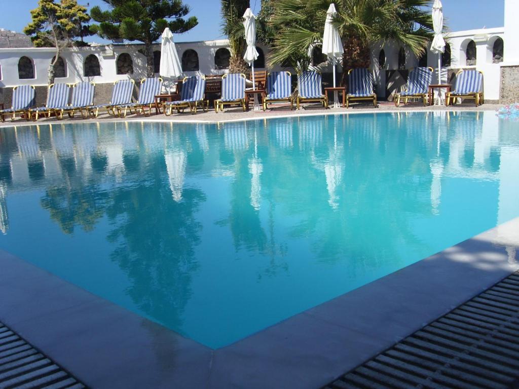 卡马利甜心一室公寓酒店的一个带蓝色椅子的游泳池,棕榈树