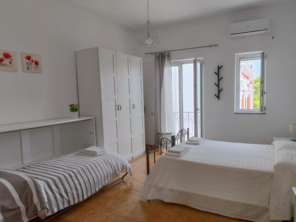利帕里A Casicedda的一间白色卧室,配有两张床和窗户