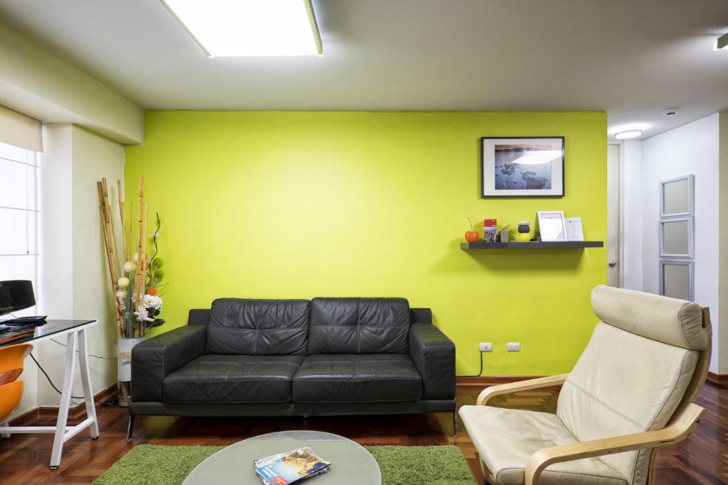 利马La Masia Apartments的客厅设有黑色沙发和黄色的墙壁