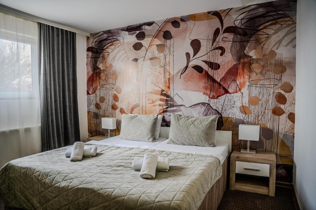 斯雷姆斯卡米特罗维察Plaza La - Night and Spa的一间卧室设有一张带花卉墙壁的大床