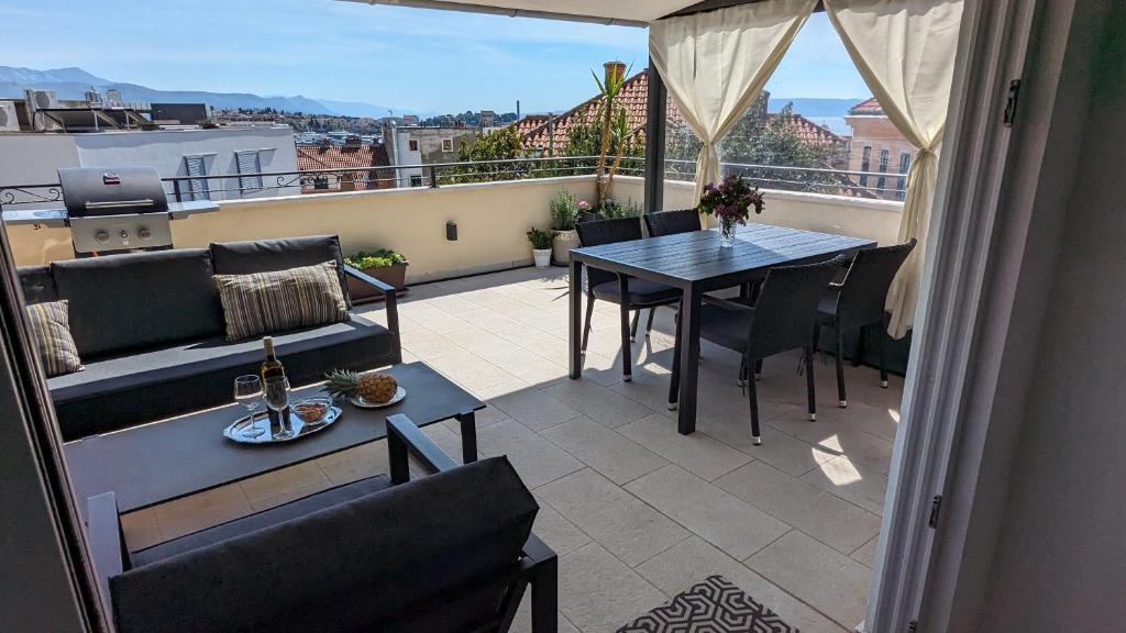 斯普利特Prime Location Penthouse apt with a large terrace的阳台配有桌子、沙发和桌子。