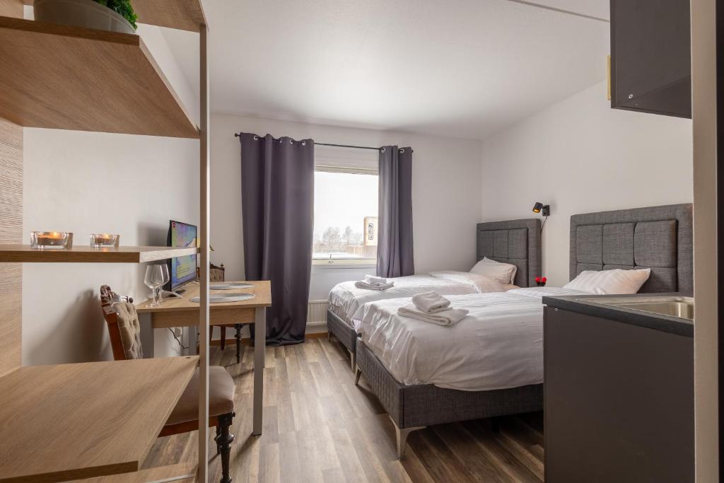 哈尔姆斯塔德Halmstad Hotel Apartments的酒店客房设有两张床、一张书桌和一个厨房。