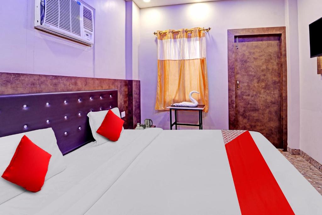 巴特那Flagship Saharsh Hotel的一间卧室配有一张带红色枕头的大床