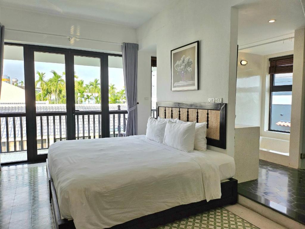 Hiếu NhơnÉn Garden Resort Hoian的一间卧室设有一张大床和一个阳台