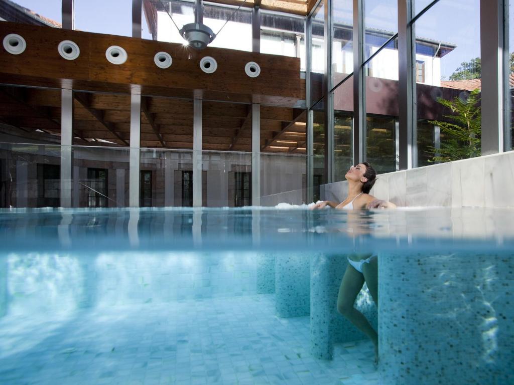 拉斯卡尔达斯Gran Hotel Las Caldas by blau hotels的坐在游泳池浴缸中的女人