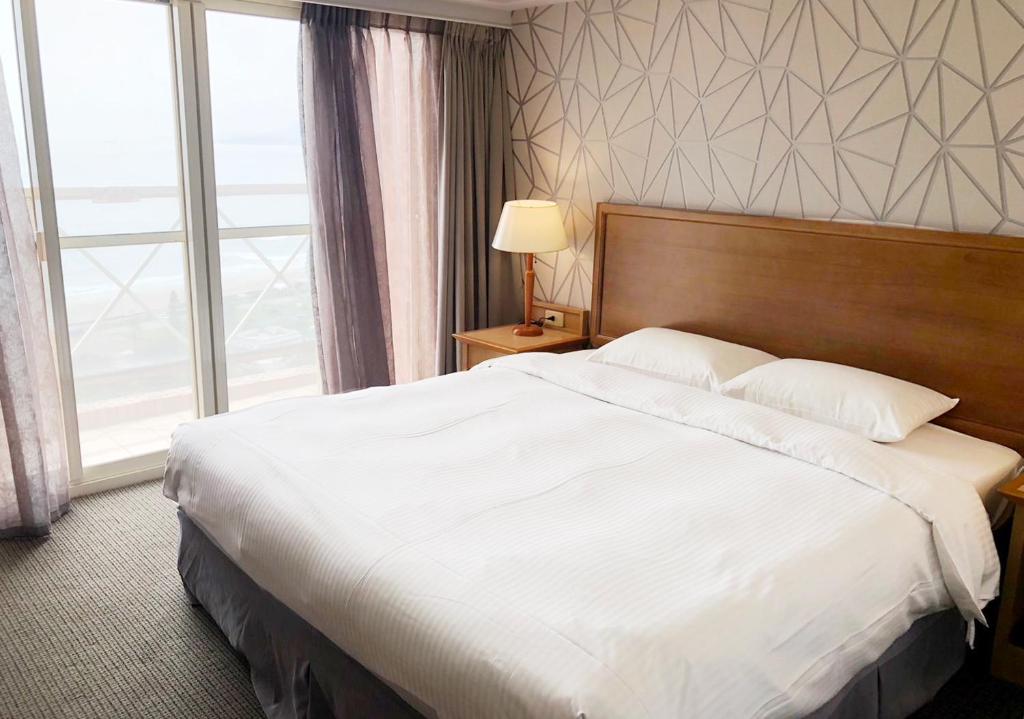 万里区福泰翡翠湾渡假饭店的一张位于酒店客房的大床,设有大窗户