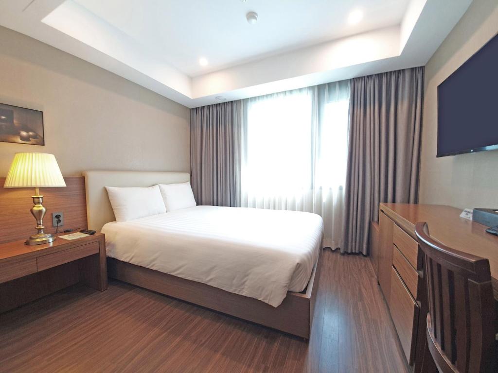 釜山釜山商务酒店的配有一张床和一张书桌的酒店客房