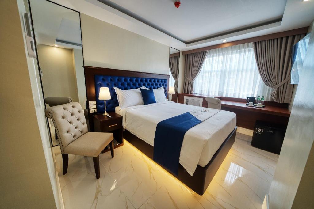 TaytayMonaco Hotel的配有一张床和一把椅子的酒店客房