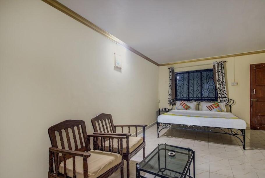 卡兰古特Super OYO Pravin Holiday Homes的一间卧室配有一张床、两把椅子和一张桌子