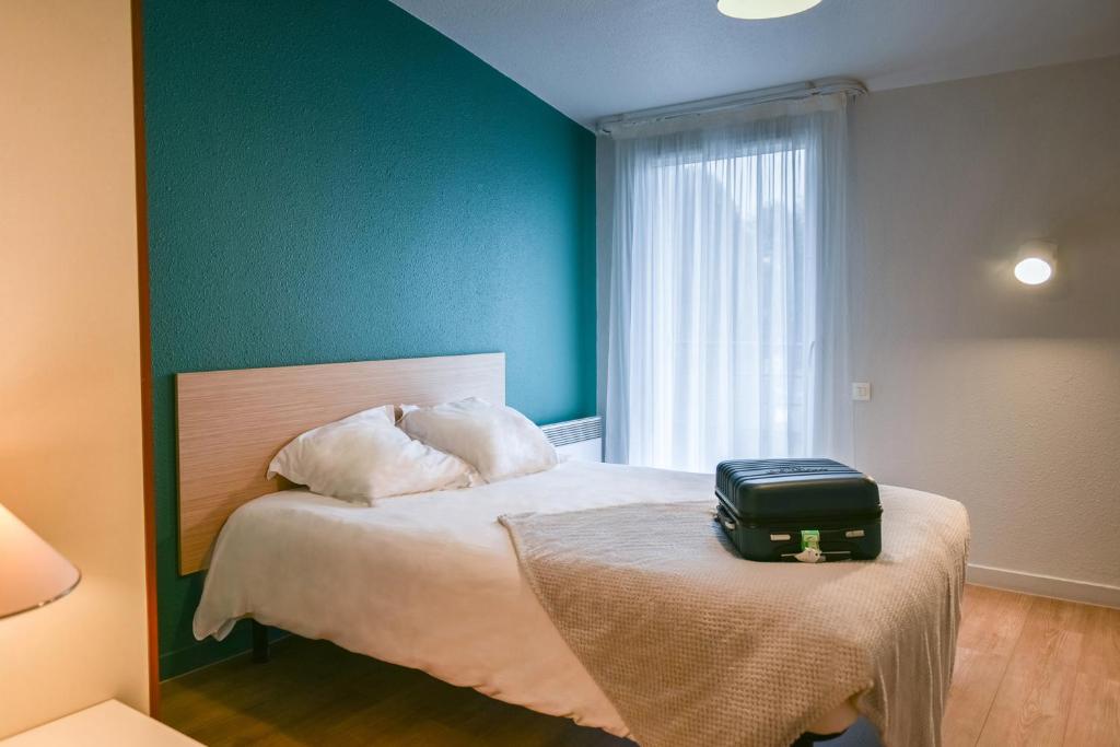 布雷斯特法国布雷斯特泰尔公寓式酒店的一间卧室,配有一张带桌子上手提箱的床