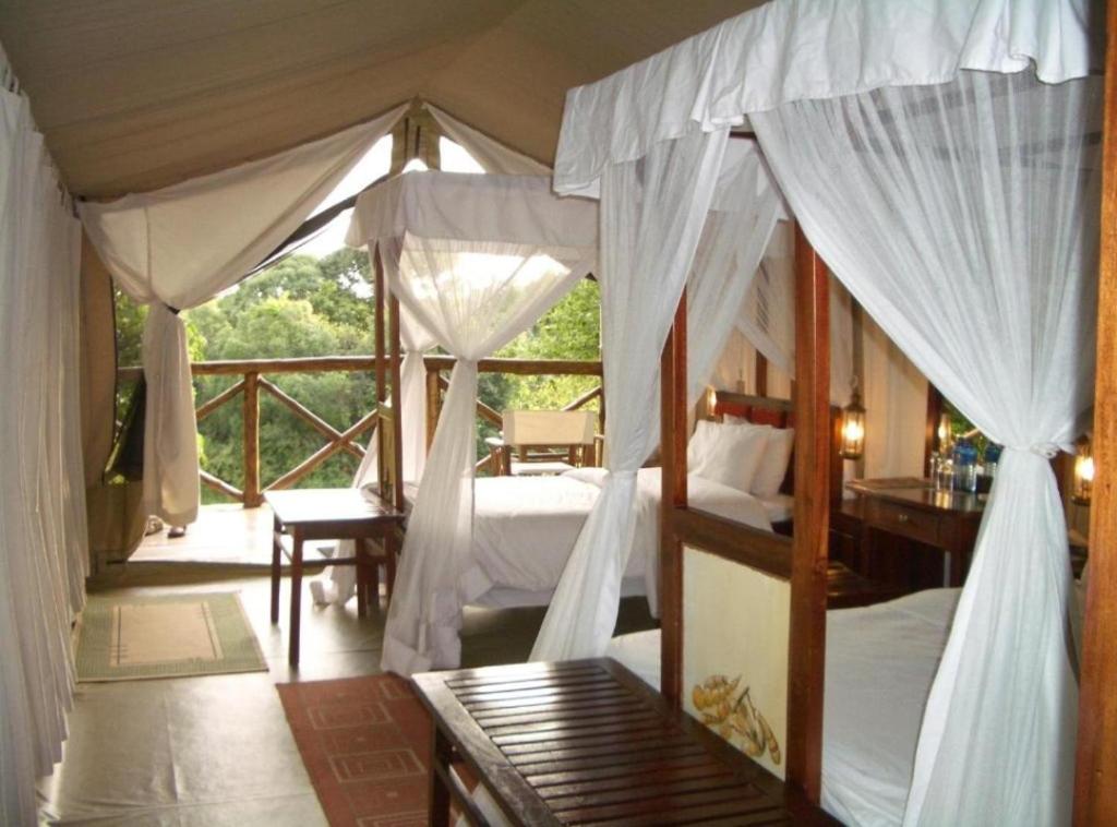 Sekenanisunshine maasai Mara safari camp in Kenya的一间带两张床的卧室和一个阳台