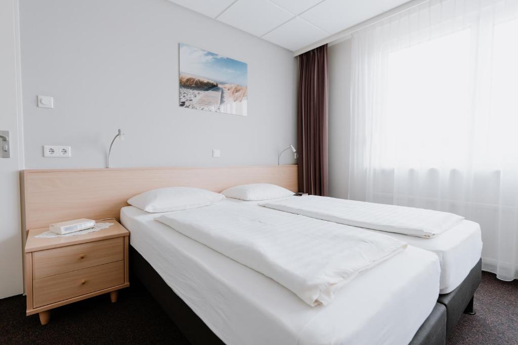 阿赫特克克Hotel Kodde的一间卧室设有两张床和床头柜