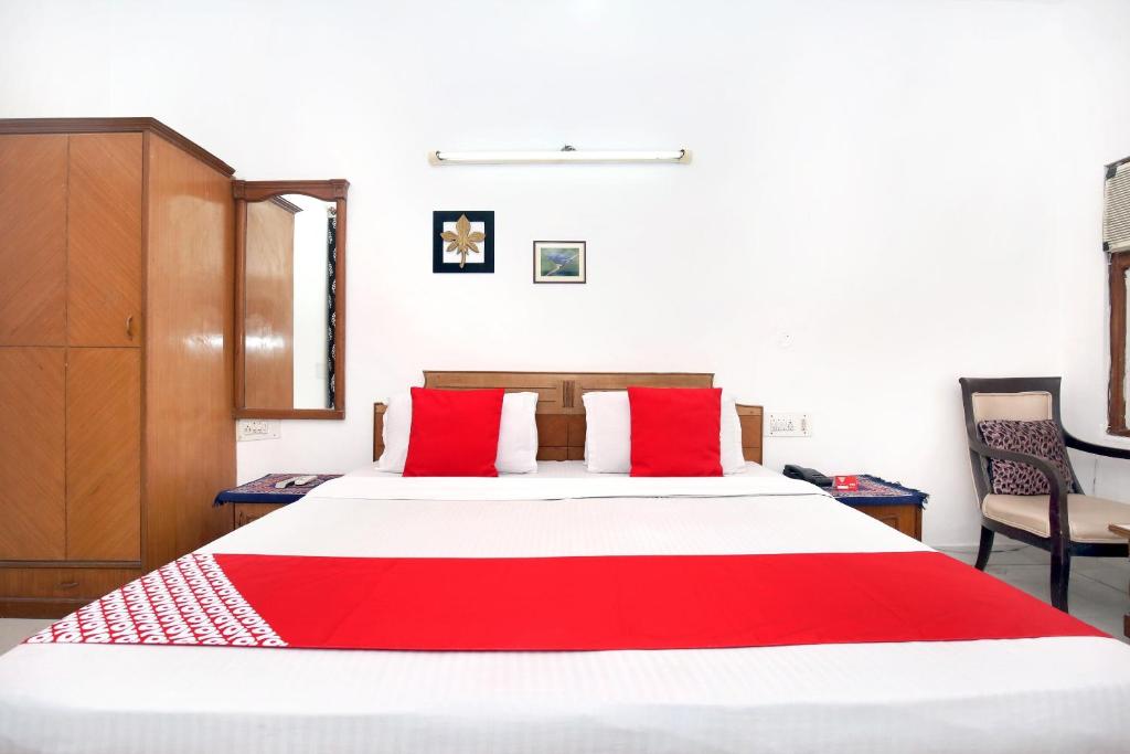 阿姆利则昆士兰酒店 的一间卧室配有一张带红色枕头的大床