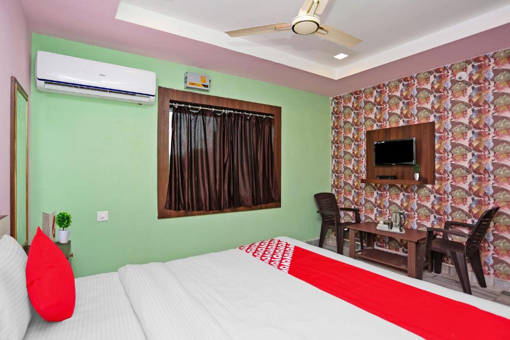 KhandagiriCapital O Hotel Aryan的一间卧室配有一张床、一张桌子和一台电视