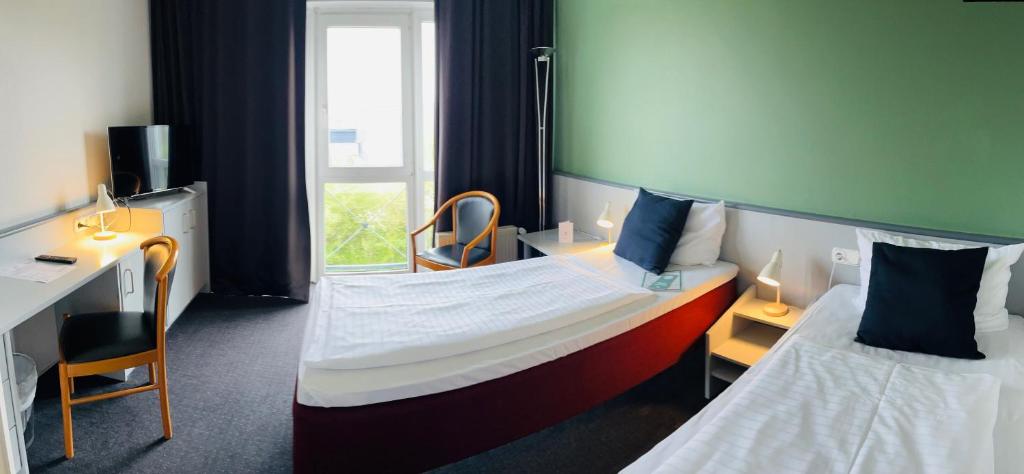 巴特奥尔德斯洛Good Morning + Bad Oldesloe的酒店客房设有两张床、一张书桌和一个窗户。