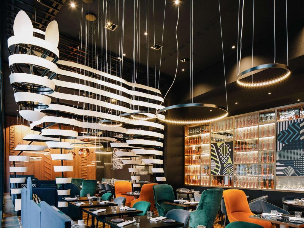 柏林铂尔曼柏林施维泽霍夫酒店的餐厅设有桌椅和吊灯。