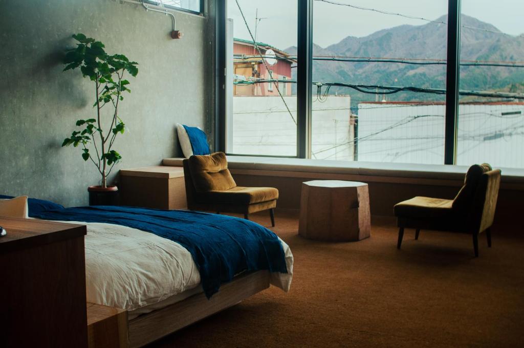 富士吉田市HOSTEL SARUYA 的一间卧室配有一张床和两把椅子,并设有一个大窗户