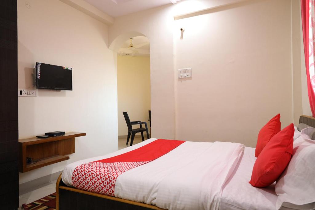 DhantoliOYO Prithvi Inn的一间卧室配有一张带红色枕头的床和电视。