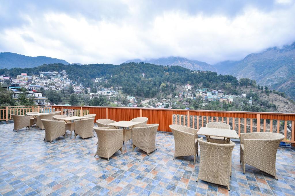 麦罗肯机Hotel Pawan Regency Mcleodganj的一组桌椅,位于一个享有山景的阳台