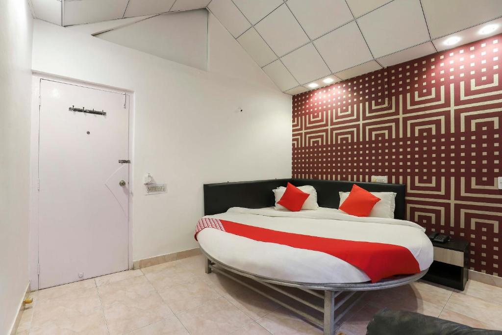 苏拉特OYO Nova Dumas Homestay的一间卧室配有一张带红色枕头的大床