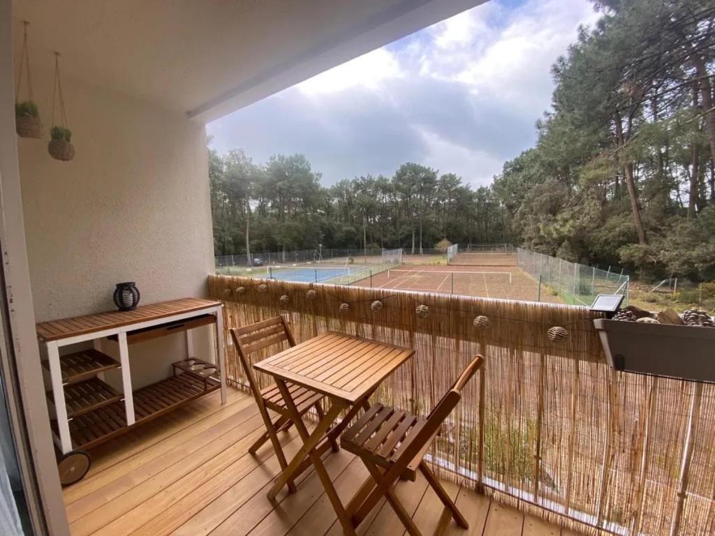 滨海雅尔Appartement au Parc de la Grange的一个带桌椅的阳台和一个网球场