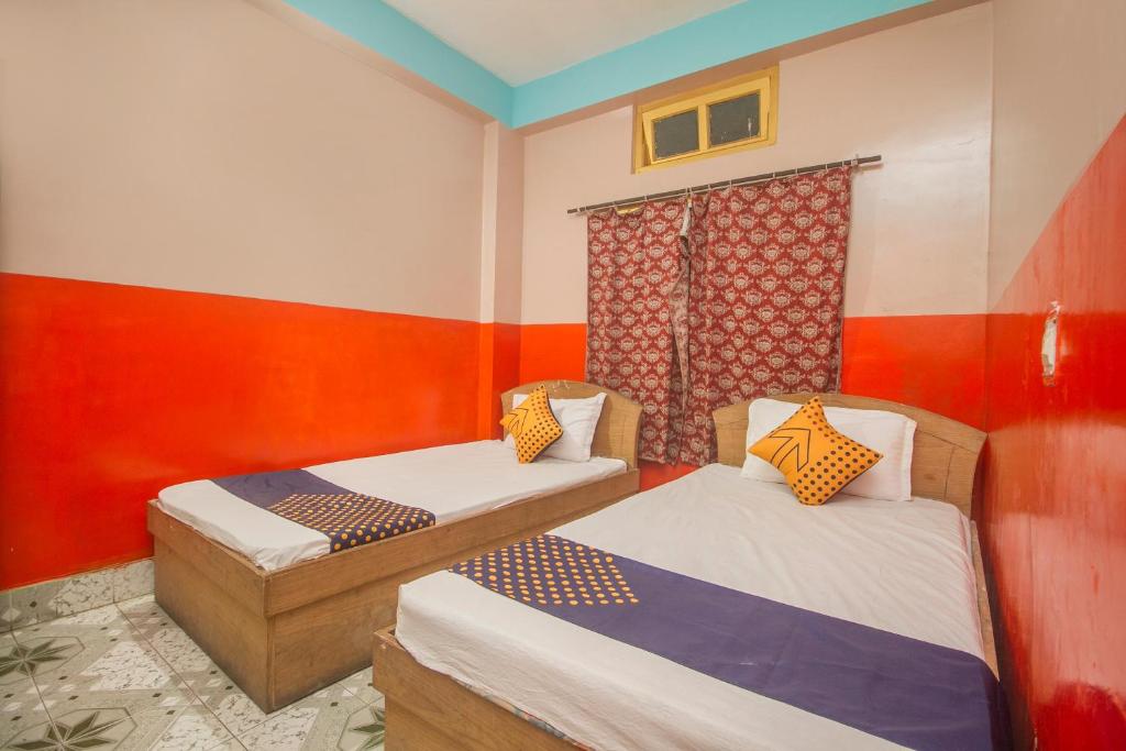Alīpur DuārOYO Hotel Chitra的红色和白色墙壁的客房内的两张床