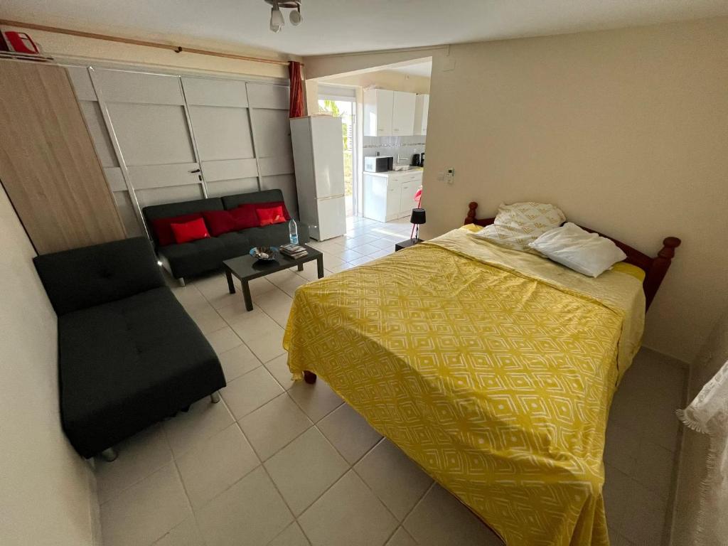 勒拉芒坦Studio avec jardin clos et wifi a Le Lamentin a 5 km de la plage的一间卧室配有黄色的床和沙发