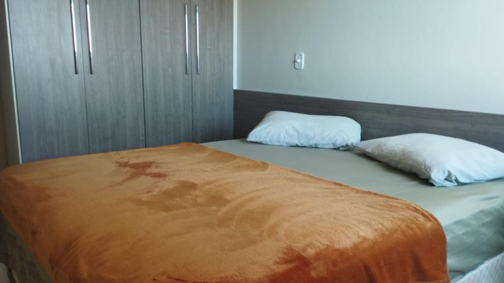 多拉杜斯Quarto Confortável Centro e perto de Hospital的一张带橙色毯子和两个枕头的床