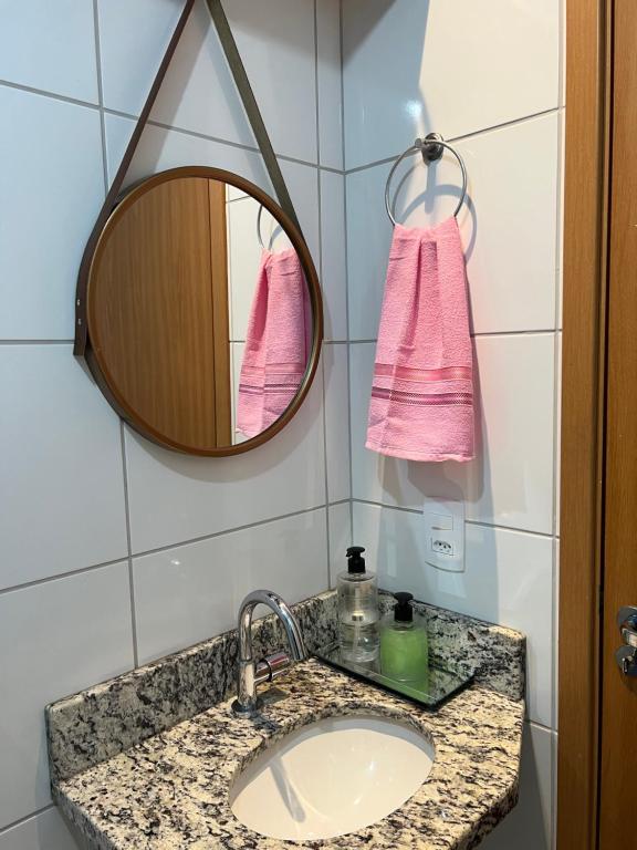 贝廷Apartamento aconchegante em Betim的浴室水槽配有镜子和粉红色毛巾