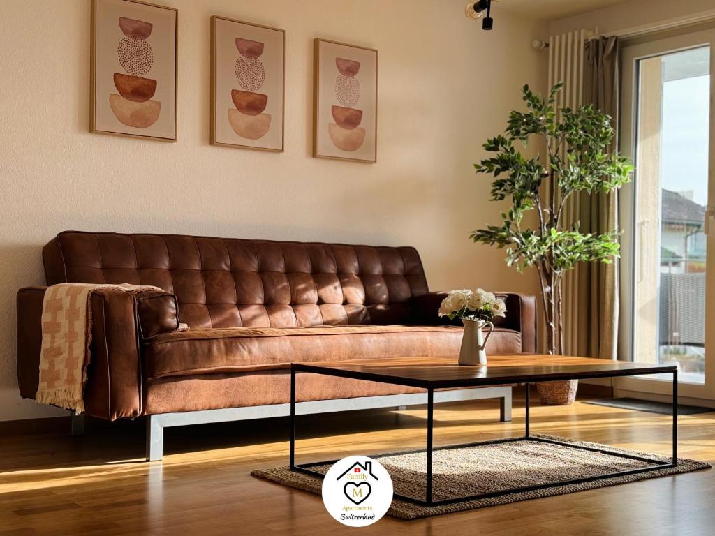 森帕赫Family M Apartments 7的客厅里一张棕色的皮沙发,配有桌子