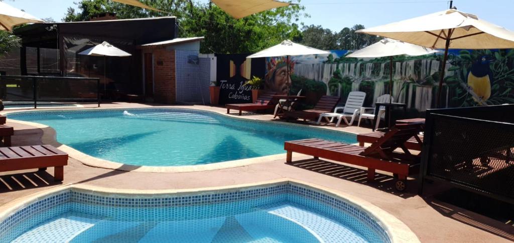 伊瓜苏港Terra Iguazú Cabañas的毗邻带长椅和遮阳伞的游泳池