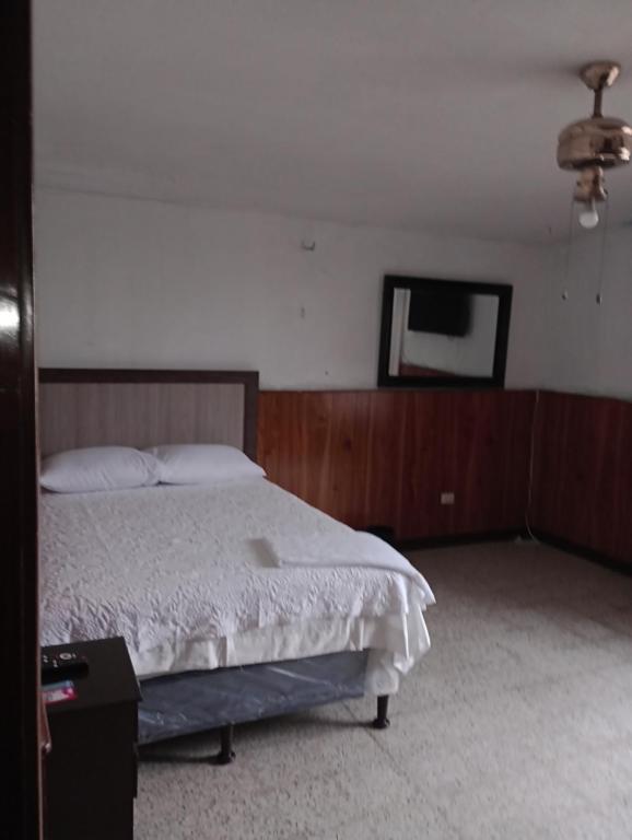 危地马拉Mundo Hostal的一间卧室配有一张床和一台平面电视