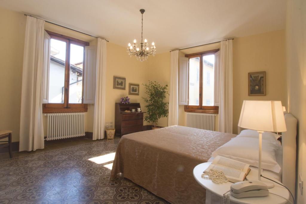佛罗伦萨迪莫拉皮耶里公寓的一间卧室配有一张床、一盏灯和两个窗户