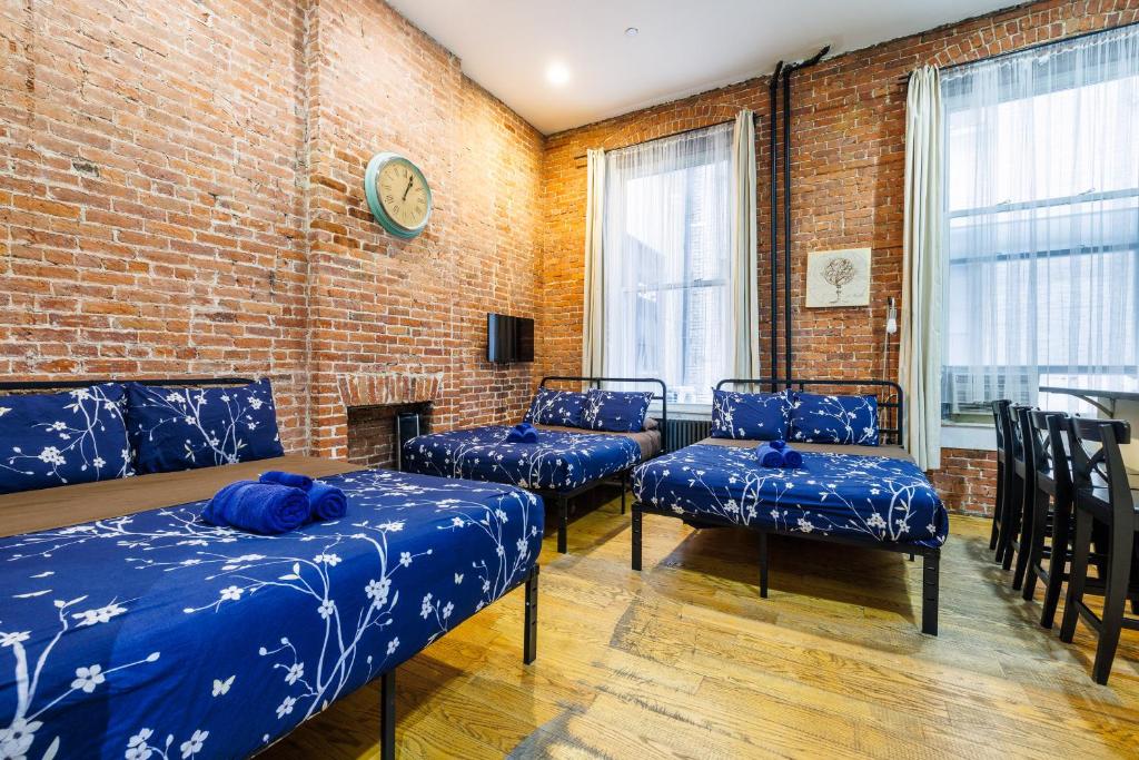 纽约Studios in New York的一间设有蓝色床和椅子的客房,拥有砖墙