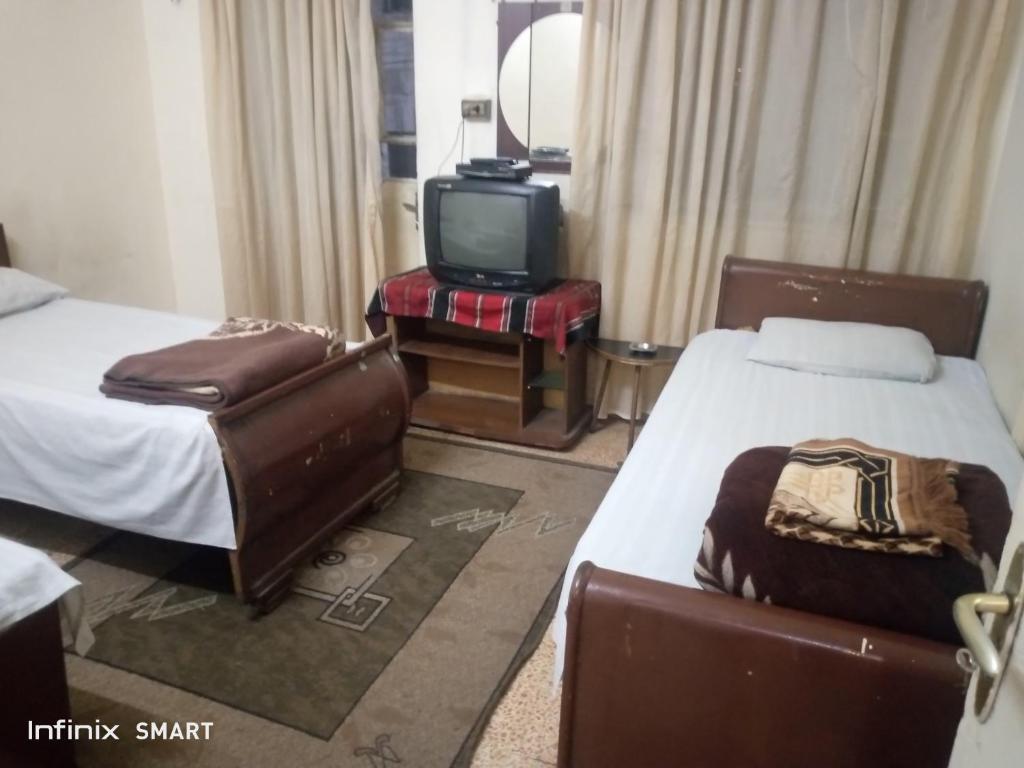 安曼Al Amawi Hostel的一间酒店客房,设有两张床和电视