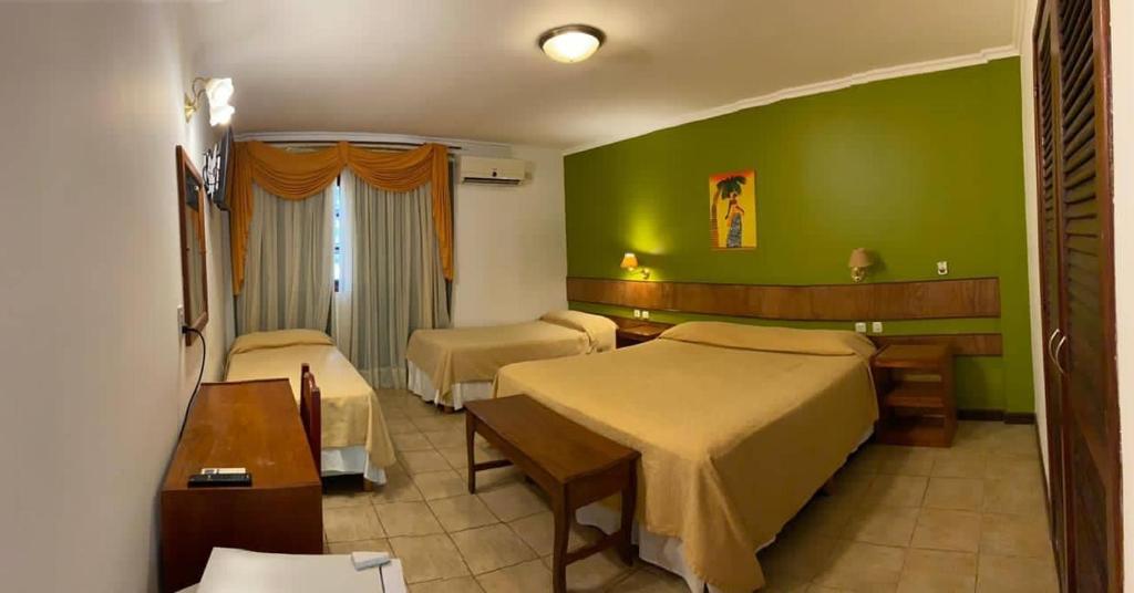 伊瓜苏港Hotel Cabañas del Leñador的一间酒店客房,设有两张床和绿色的墙壁