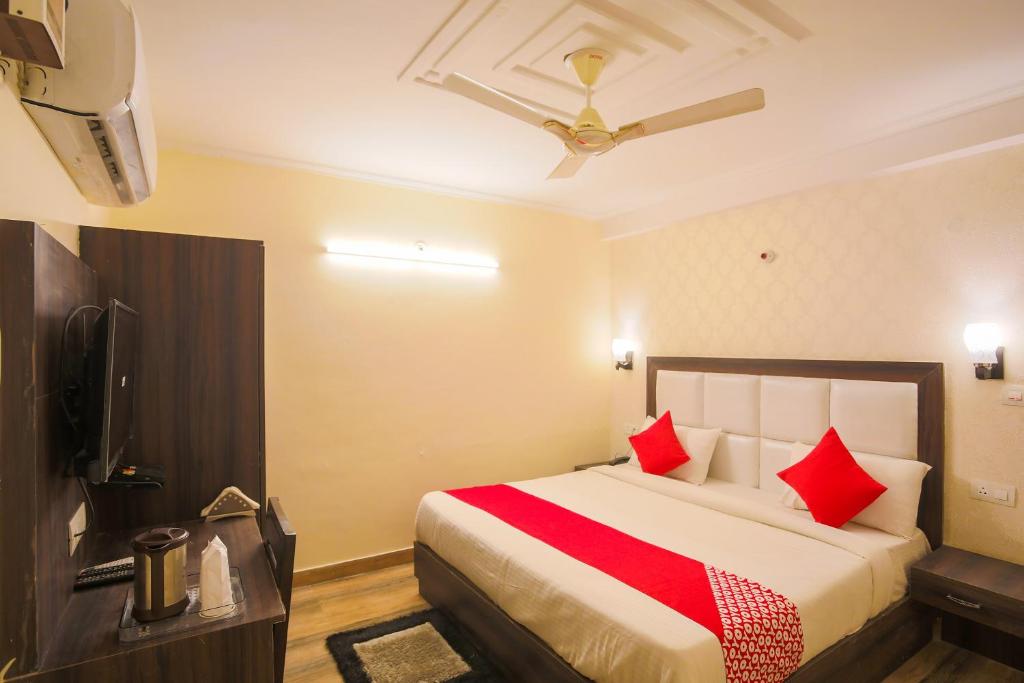 法里达巴德OYO Flagship Hotel Lazeeno的一间卧室配有一张带红色枕头的大床