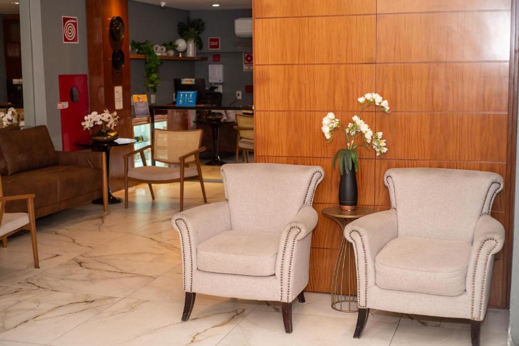 尤西德福拉Nobile Hotel Juiz de Fora的大堂设有两把椅子和一张花瓶桌子
