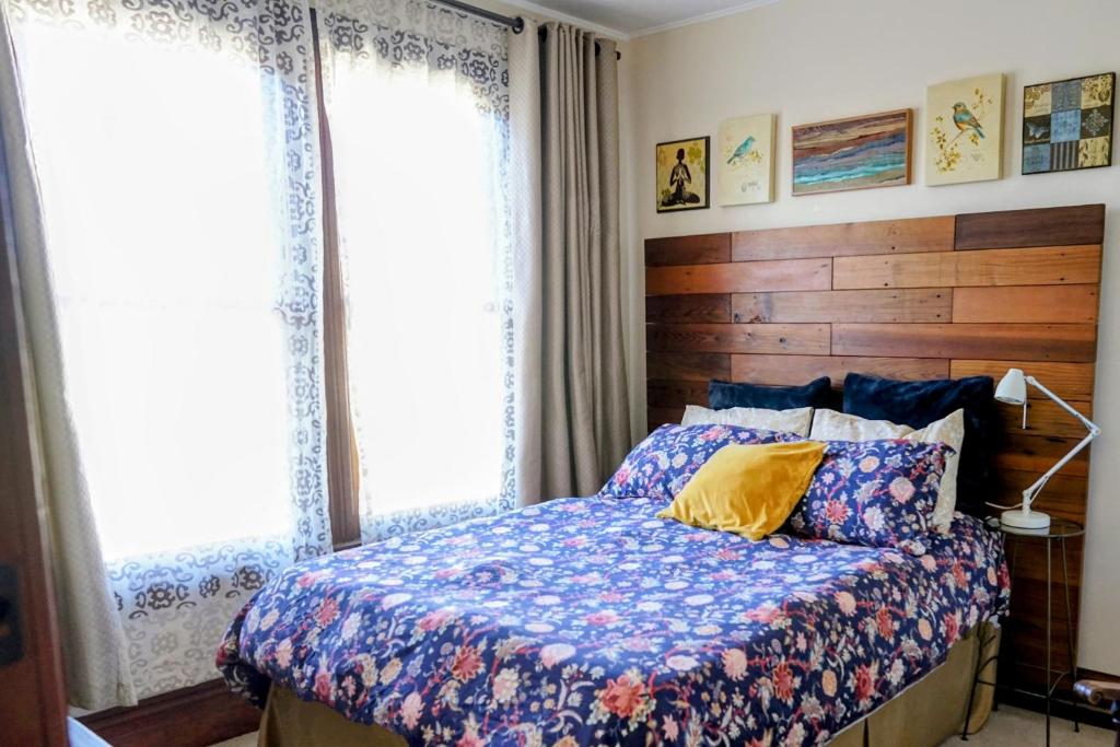 旧金山Perfect Location - 4BD,1BA - Restored Redwood Home的一间卧室配有一张带木制床头板的床和两个窗户。