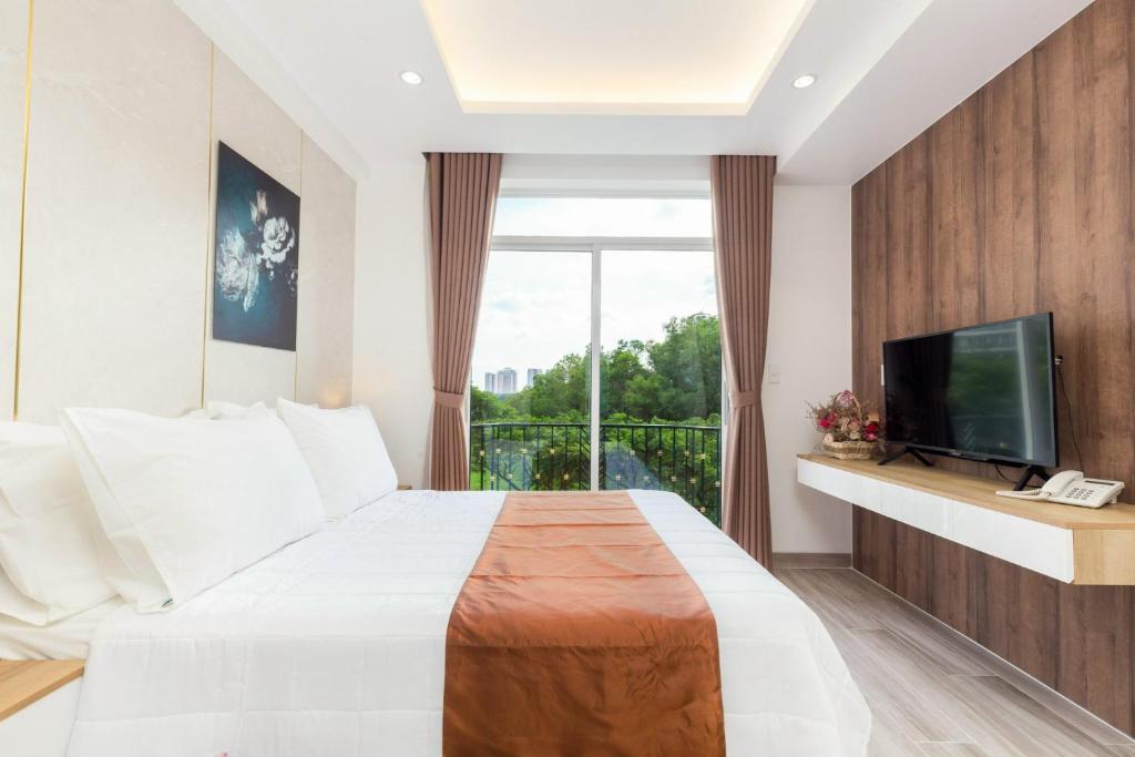胡志明市NiNa APARTHOTEL的一间卧室设有一张床、一台电视和一个阳台。