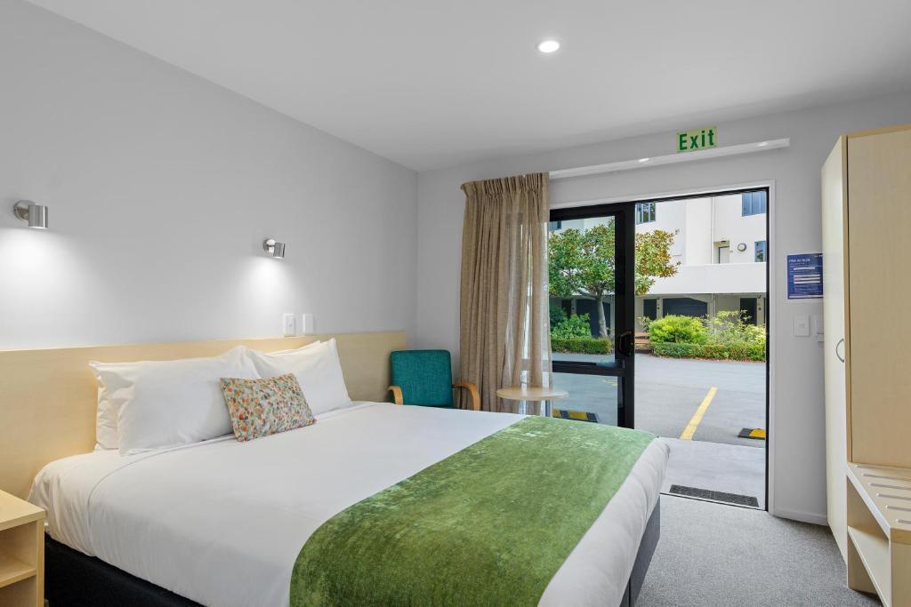 基督城Bella Vista Motel & Apartments Christchurch的酒店客房,设有床和滑动玻璃门