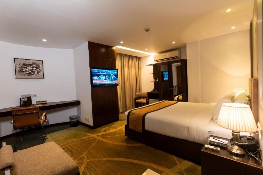 达卡孟加拉金丝雀公园酒店的酒店客房设有一张床、一张书桌和一台电视机。