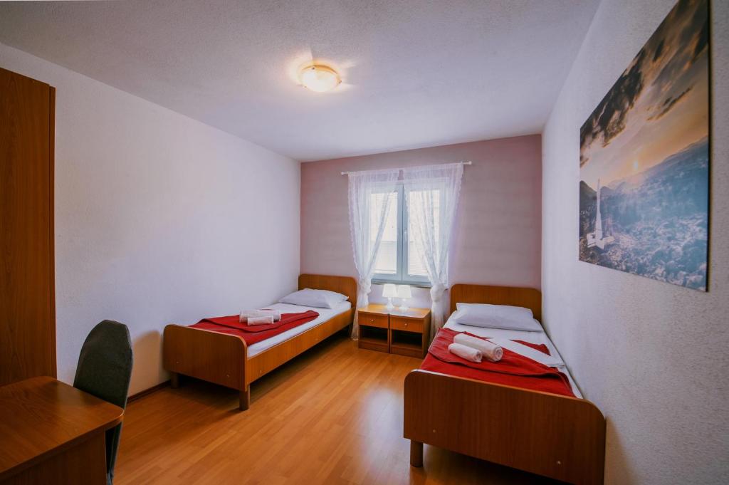 默主歌耶Villa Marinko的客房设有两张床、一张桌子和一扇窗户。