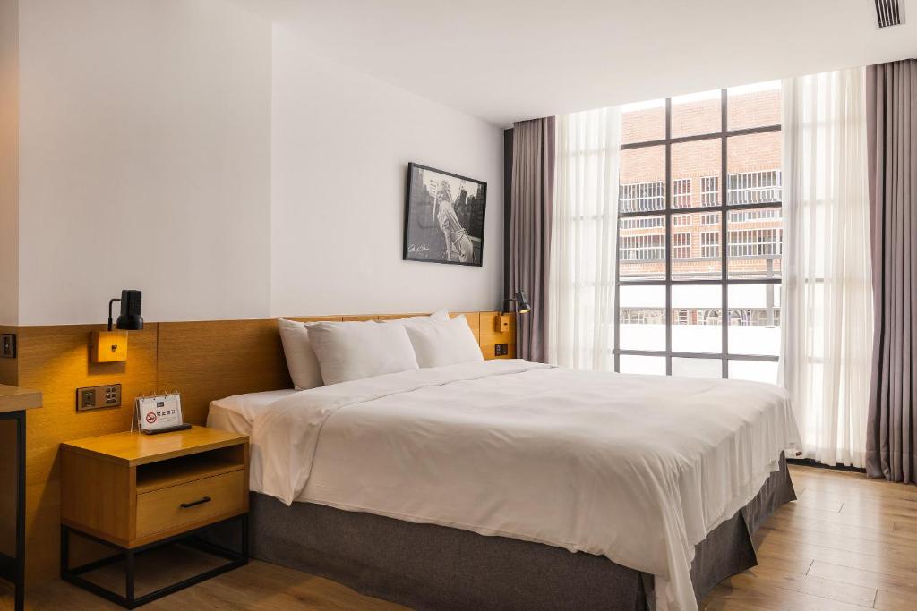 台中市新蓝天旅栈的一间卧室设有一张大床和一个大窗户