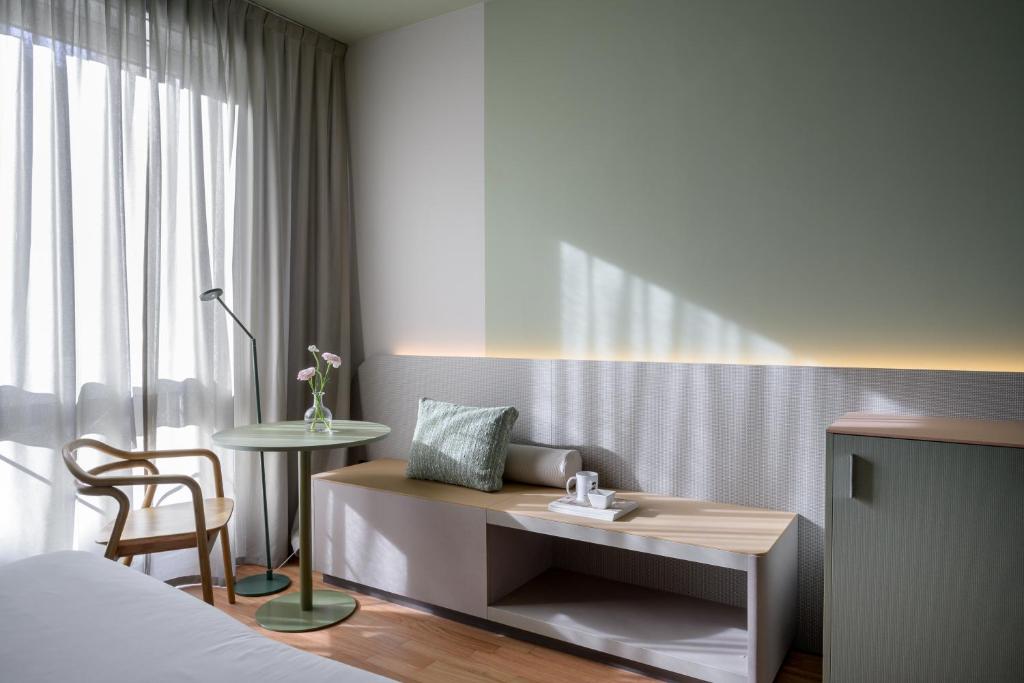 卢卡Hotel Ilaria的卧室配有1张床、1张桌子和1把椅子